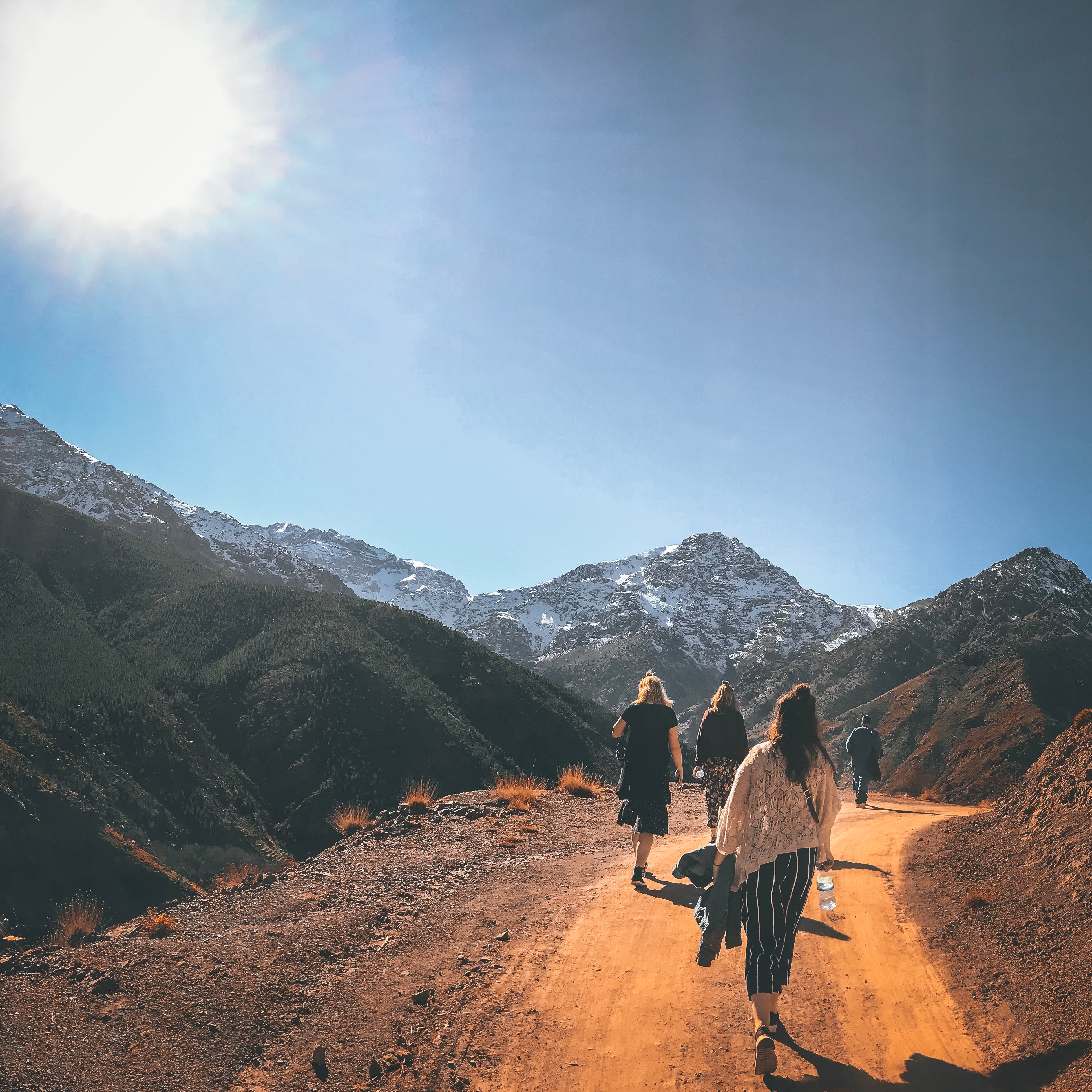 Mountains in the background with a small group of people walking on a path upwards.