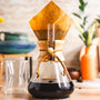 Chemex coffee maker with a paper filter on a wooden surface.